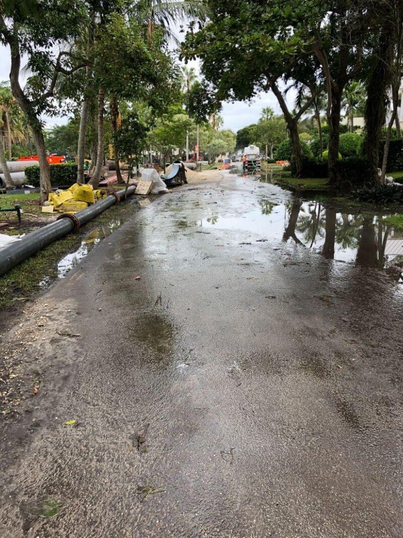 Flooded residential street with a dewatering discharge line running along the curb
