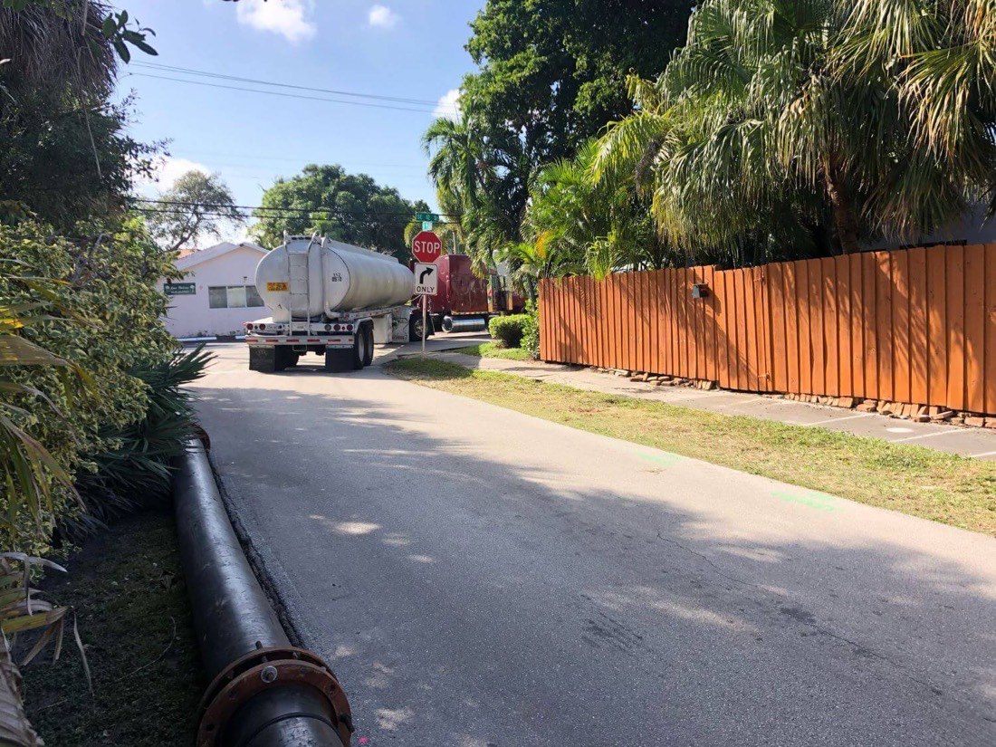FMS tanker trailer working a residential street with a discharge line along the shoulder