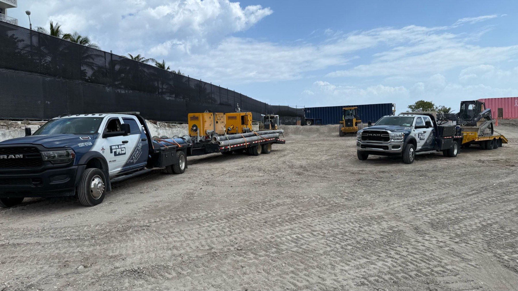 FMS service trucks, pumps and a skid steer staged on a construction site